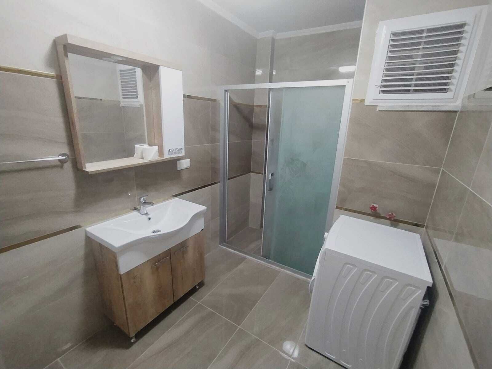 Een badkamer met een wastafel, spiegel, douche en radiator.