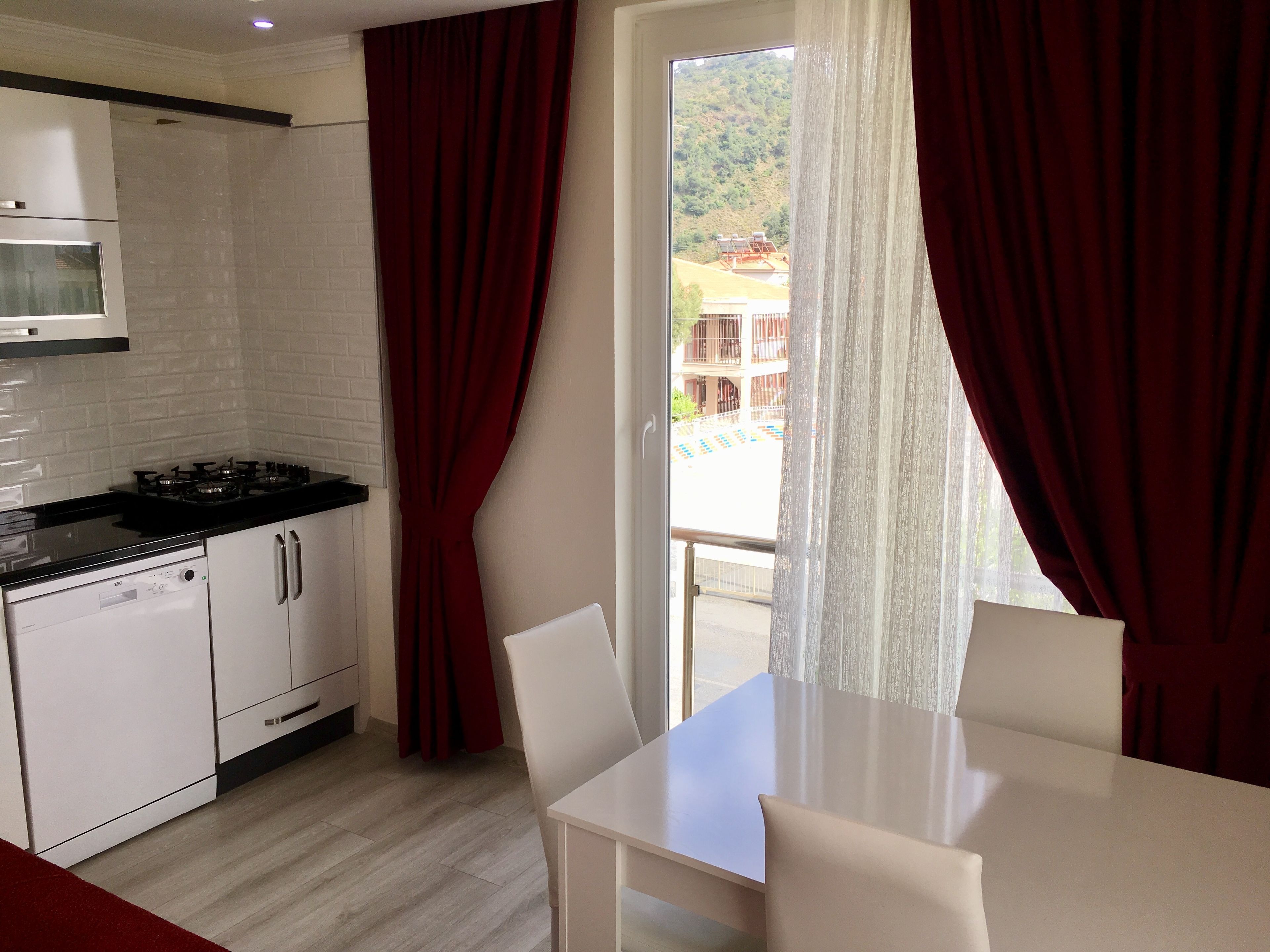 A modern kitchen with white cabinets, a gas stove, and a dining area with a table and chairs.