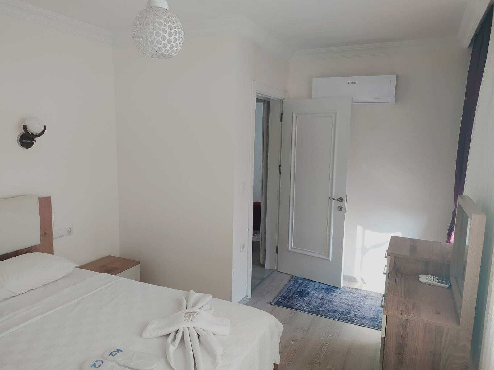 Una habitación de hotel con una cama, una mesita de noche, un armario y una puerta que da a otra habitación.