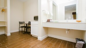 A bathroom with a white sink, mirror, and a trash bin.