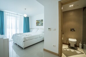 Una habitación de hotel moderna con una cama, una mesita de noche, un baño con inodoro y zona de ducha.