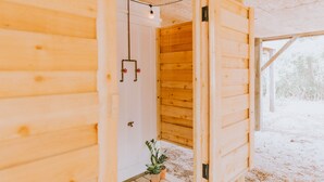 A wooden cabin interior with a door leading to a room, a hanging light fixture, and a small potted plant. - ★ "The house is perfection—stylish, comfortable + close to the beach." (Nags Head)