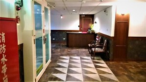 A hotel reception area with a check-in counter, a reception desk, and a seating area with chairs. - Hsinchu World Trade Business Hall (Hsinchu)
