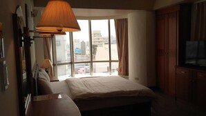 A hotel room with a large bed, a desk, a lamp, a TV, and a window with curtains. - Hsinchu World Trade Business Hall (Hsinchu)