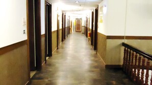 A long, narrow hallway with doors on both sides, a fire extinguisher on the right, and a handrail on the right side. - Hsinchu World Trade Business Hall (Hsinchu)