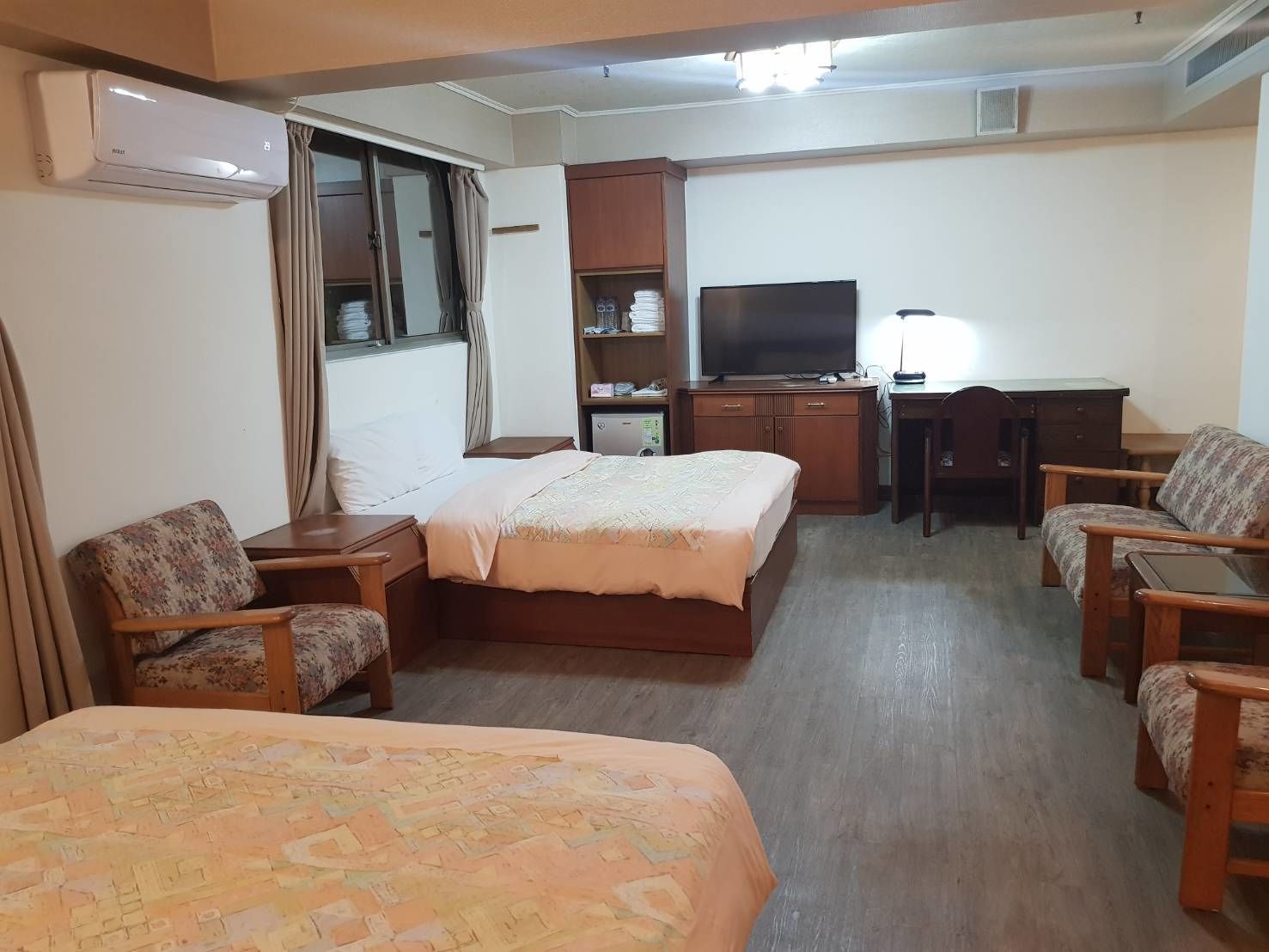 Habitación de hotel con dos camas, un escritorio, televisor y armario.