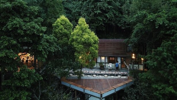 A wooden deck with tables and chairs, surrounded by dense forest. - Deep Breath B&B (Shoufeng)