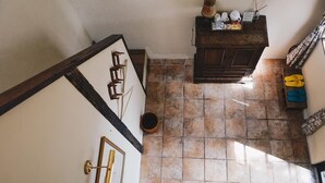 A narrow hallway with a tiled floor, a wooden cabinet with various items, and a pair of yellow slippers on the floor. - Deep Breath B&B (Shoufeng)