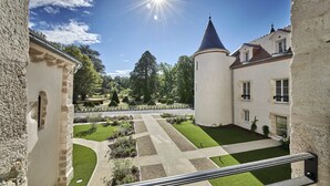 A courtyard with a lawn, pathways, and a tower. - Château Saint-Jean (Montlucon)