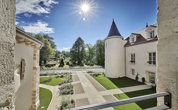 A courtyard with a lawn, pathways, and a tower. - Château Saint-Jean (Montlucon)