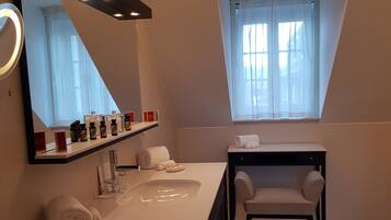A modern bathroom with a large mirror, a vanity with a sink, a chair, and a window with curtains.