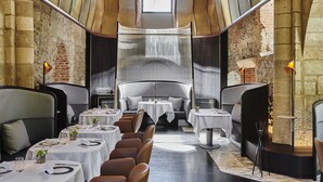 A restaurant with a vaulted ceiling, stone walls, and a central seating area with tables and chairs. - Château Saint-Jean (Montlucon)
