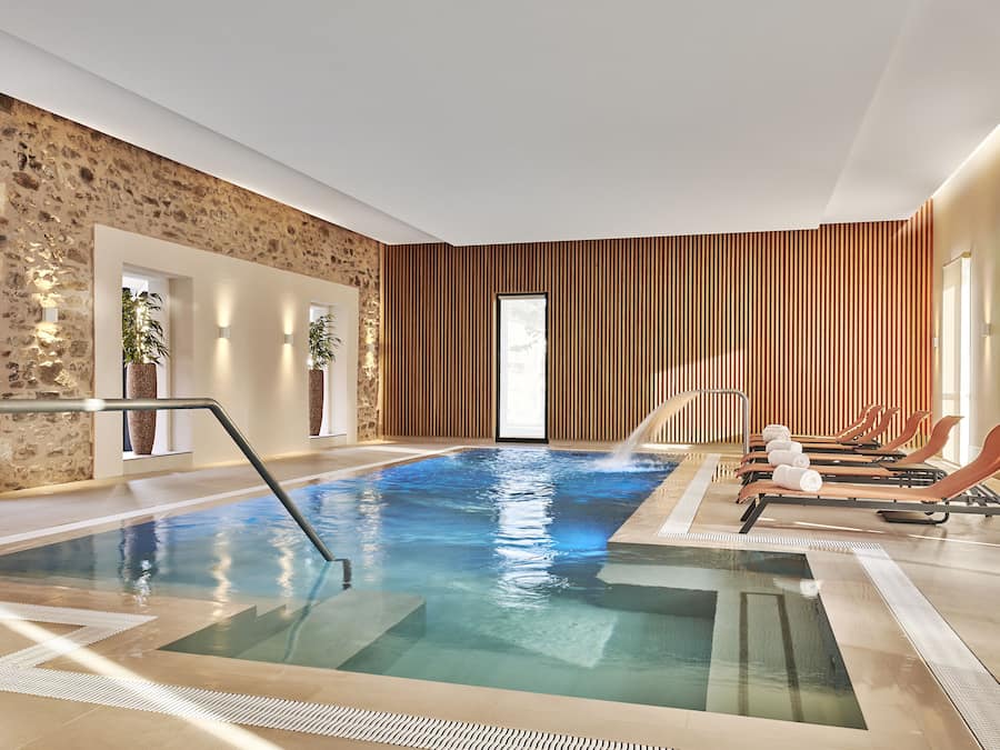 Een binnenzwembad, ligstoelen bij het zwembad