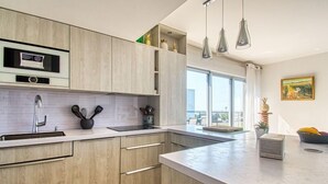 A modern kitchen with wooden cabinets, a stainless steel sink, and a large window providing natural light. - Golfe Horizon by Interhome (Fréjus)