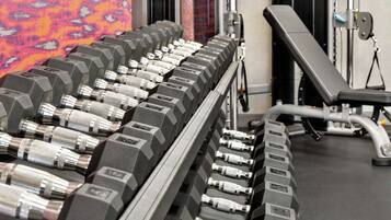 Une salle de sport avec plusieurs rangées de haltères et un banc.