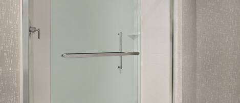 A glass-enclosed shower area with a glass door, a metal towel rack, and a tiled floor.