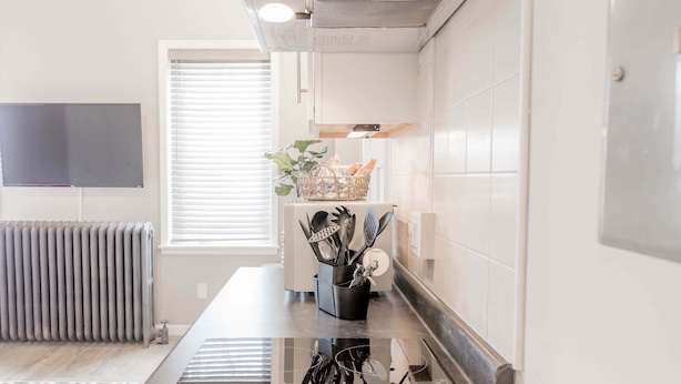 A modern kitchen with white cabinets, a black countertop, and a stainless steel range hood.