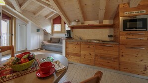 Una cocina acogedora con armarios de madera, una mesa de comedor con mantel rojo y una cesta de frutas.
