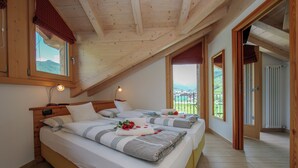 Un dormitorio con dos camas, vigas de madera en el techo y vistas a un paisaje verde.