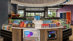 Una estación de bebidas de autoservicio con un expositor refrigerado, snacks y agua embotellada.