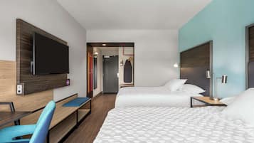 A hotel room with two beds, a desk, a chair, a TV, and a door leading to a bathroom.