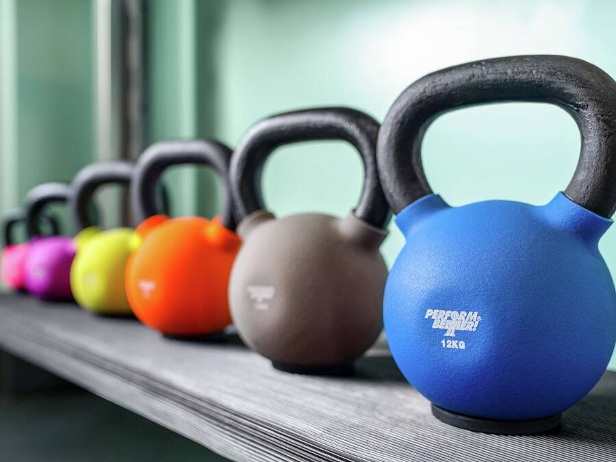 Un estante con varios kettlebells alineados.