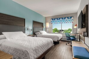 A hotel room with two beds, a desk, a chair, a TV, and a window with a view of greenery. - Tru By Hilton Hershey Chocolate Avenue (Hershey)