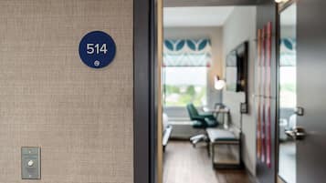 A hotel room entrance with a door number 514, a textured wall, and a glimpse of a modern interior with a green chair and a desk.