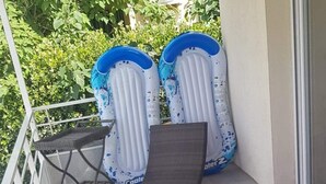 A balcony with a red polka dot tablecloth, two inflatable loungers, a wicker chair, and a wicker sofa. - Apartment with pool and magnificent views in the South of France (Saint-Chamas)