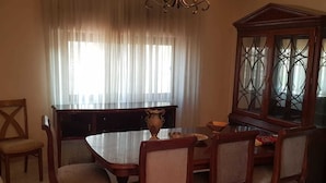 A dining room with a wooden table and chairs, a cabinet, and a piano. - Alburdini (Aqaba)