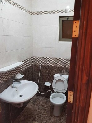 Un bagno piccolo con lavandino, due servizi igienici e pavimento piastrellato.