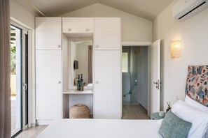 Een slaapkamer met een bed, een kledingkast, een spiegel, een klein tafeltje en een wandlamp.