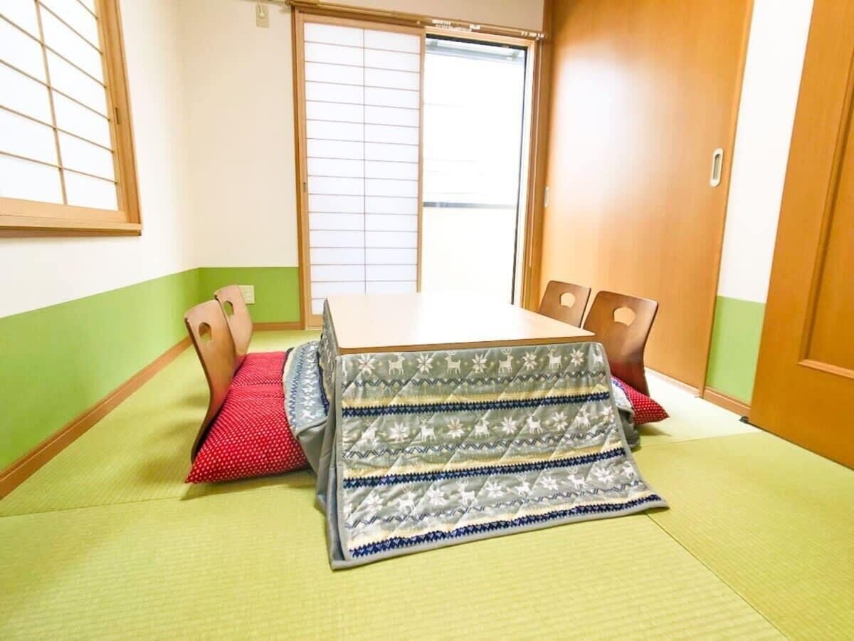 Ein Raum mit Tatami-Matten, einer Schiebetür, einem Tisch und Stühlen.