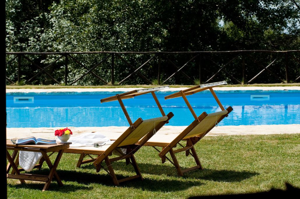 A poolside area with lounge chairs and a table with a book and flowers.