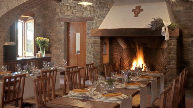A dining area with stone walls, wooden tables, and a fireplace. - Le Case Residenza di Campagna (Assisi)