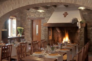 Un comedor con paredes de piedra, mesas de madera y chimenea.