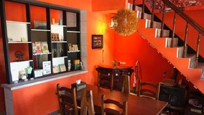 A restaurant with a wooden dining table and chairs, a counter with various items, and a staircase. - Hey Bear B&B Jiufen (New Taipei City)