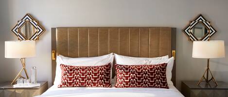 A hotel room with a large bed, two bedside tables with lamps, and decorative wall mirrors.