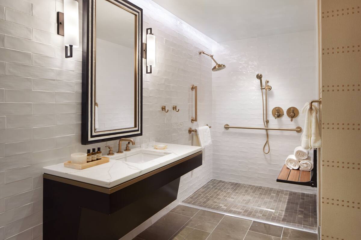 A modern bathroom with a large mirror, two sinks, a shower, and a towel rack.