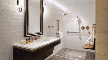 A modern bathroom with a large mirror, two sinks, a shower, and a towel rack.