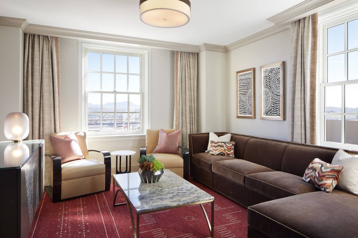 A modern living room with a sofa, armchairs, a coffee table, and a view of the city.
