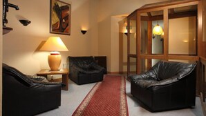 Une pièce avec deux canapés en cuir, un tapis rouge à motifs, une lampe et un tableau au mur.