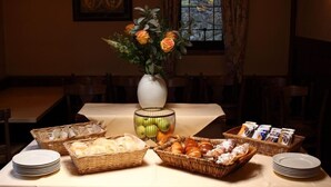 Une table à manger dressée avec divers plats, un vase rempli de fleurs et une fenêtre donnant sur un beau paysage.