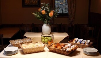 Una mesa de comedor preparada con diferentes alimentos, un jarrón con flores y una ventana con vistas.