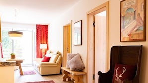 Un salon chaleureux avec un canapé, un banc en bois, un tapis rouge et un tableau encadré au mur.
