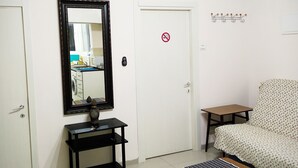 Ein Zimmer mit einem Bett, einem kleinen Tisch, einem Spiegel und einer Tür mit einem Rauchverbot-Schild.