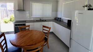 Eine kleine Küche mit weißen Schränken, einem Holztisch und einem Kühlschrank.