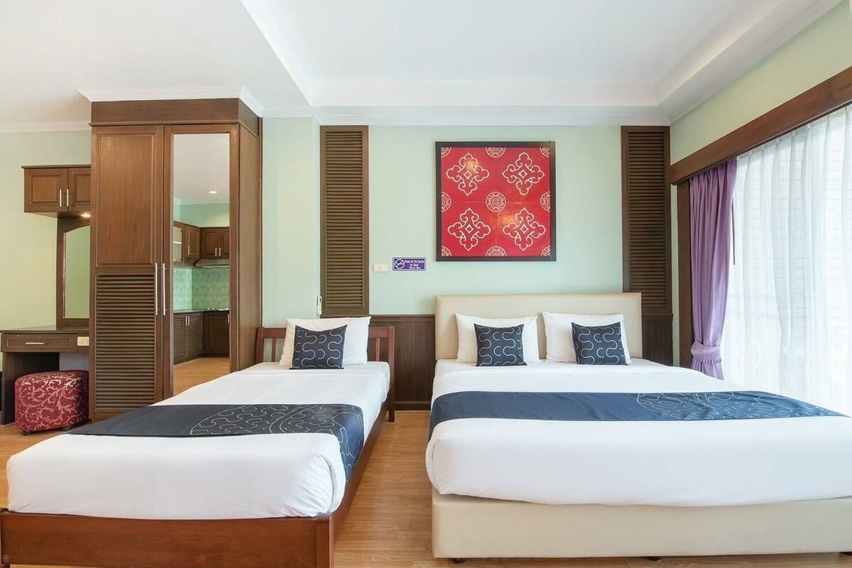Ein Hotelzimmer mit zwei Betten, einem Schreibtisch, einem Spiegel und einem roten Wanddekor.