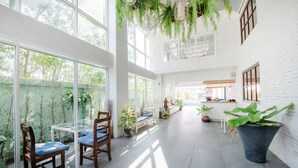 A spacious indoor area with large windows, a dining table with chairs, and several potted plants.