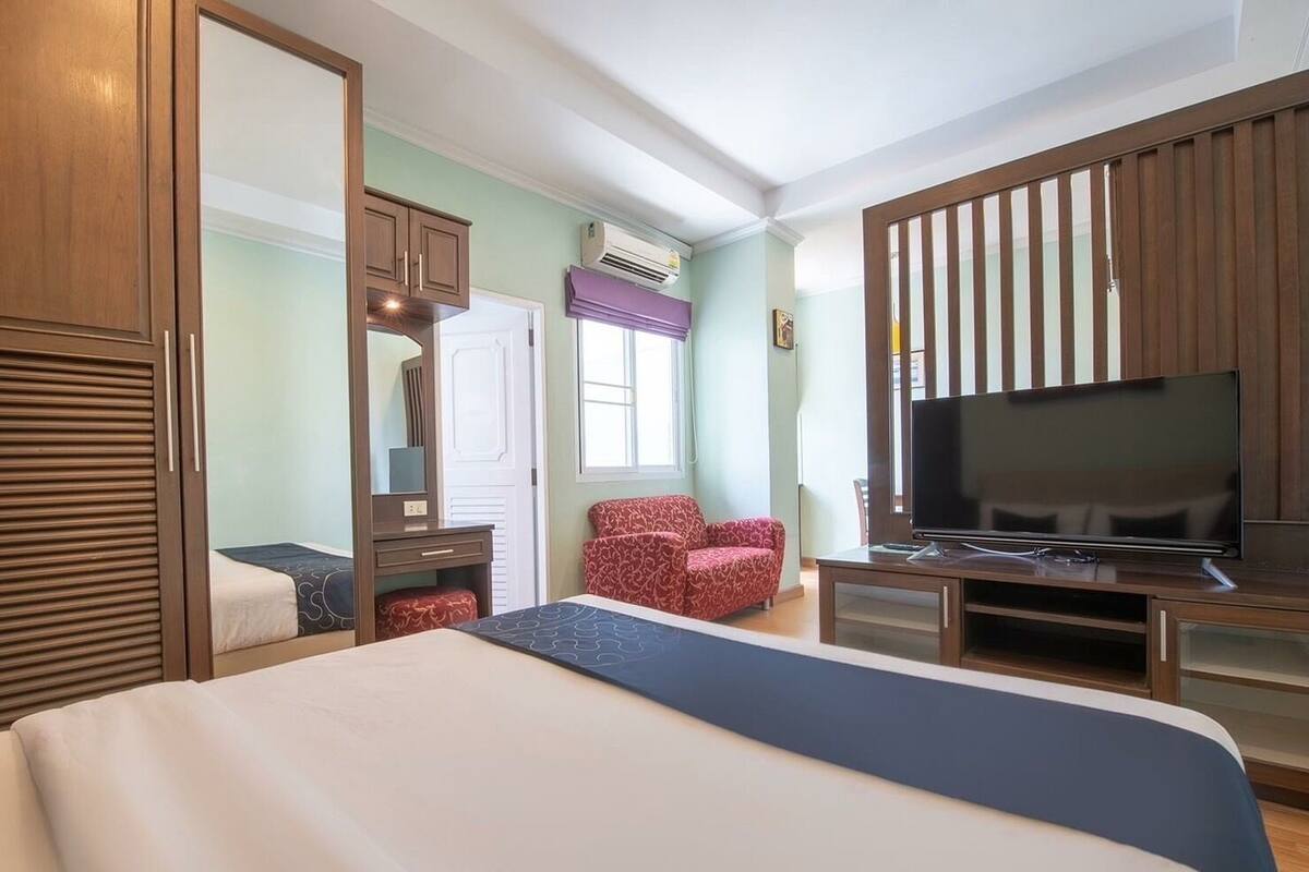 Ein Hotelzimmer mit einem großen Bett, einem Fernseher, einem Schreibtisch und einem Sessel.